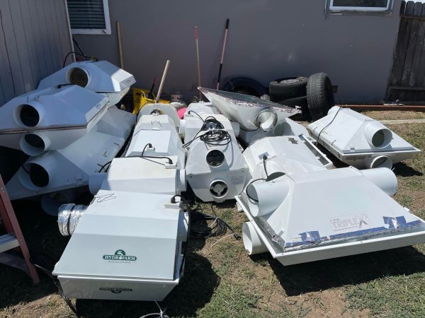 A pile of discarded white ventilation or ducting equipment scattered on the ground for junk removal.