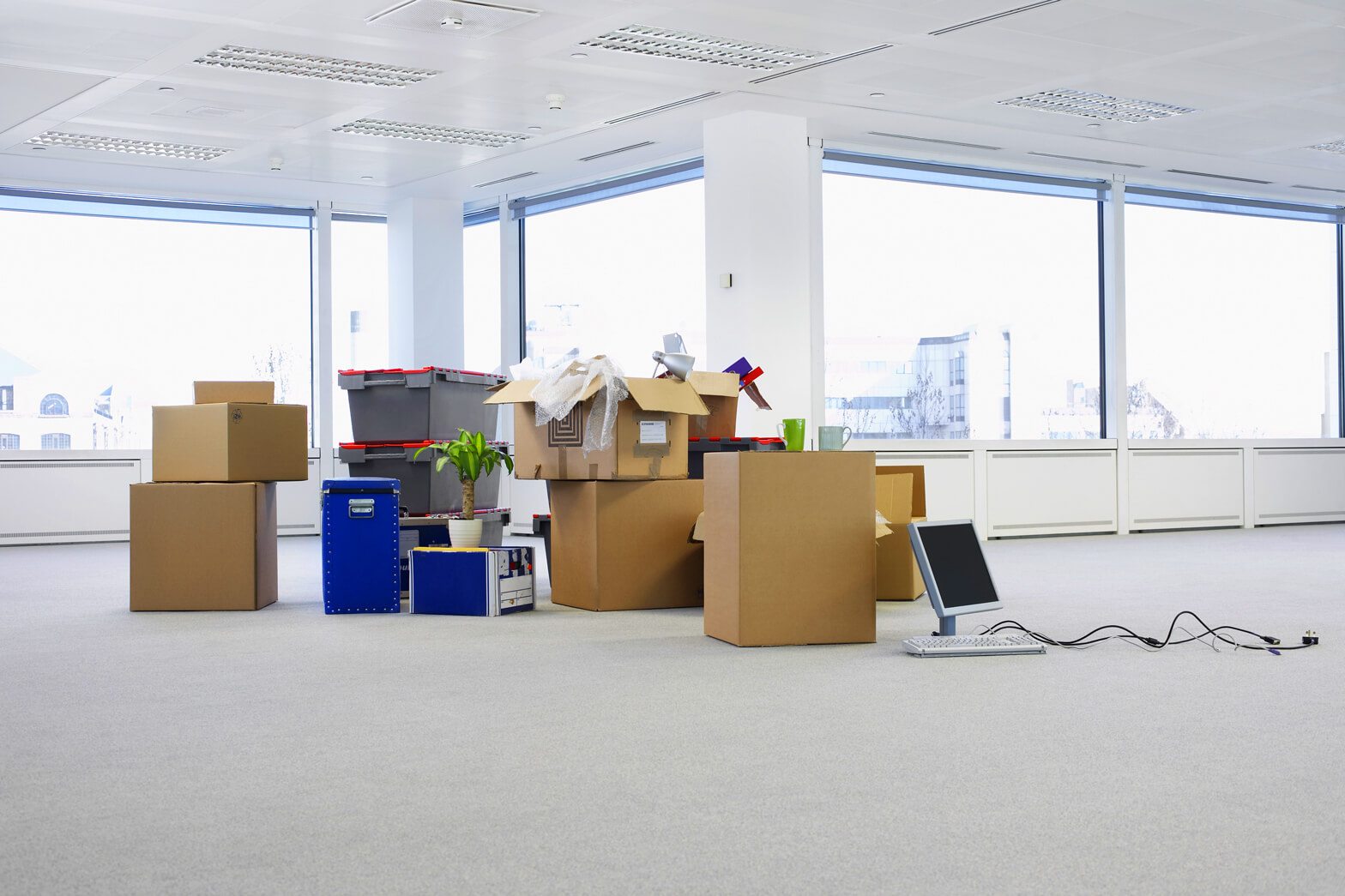 An empty, modern office space with stacks of cardboard moving boxes.